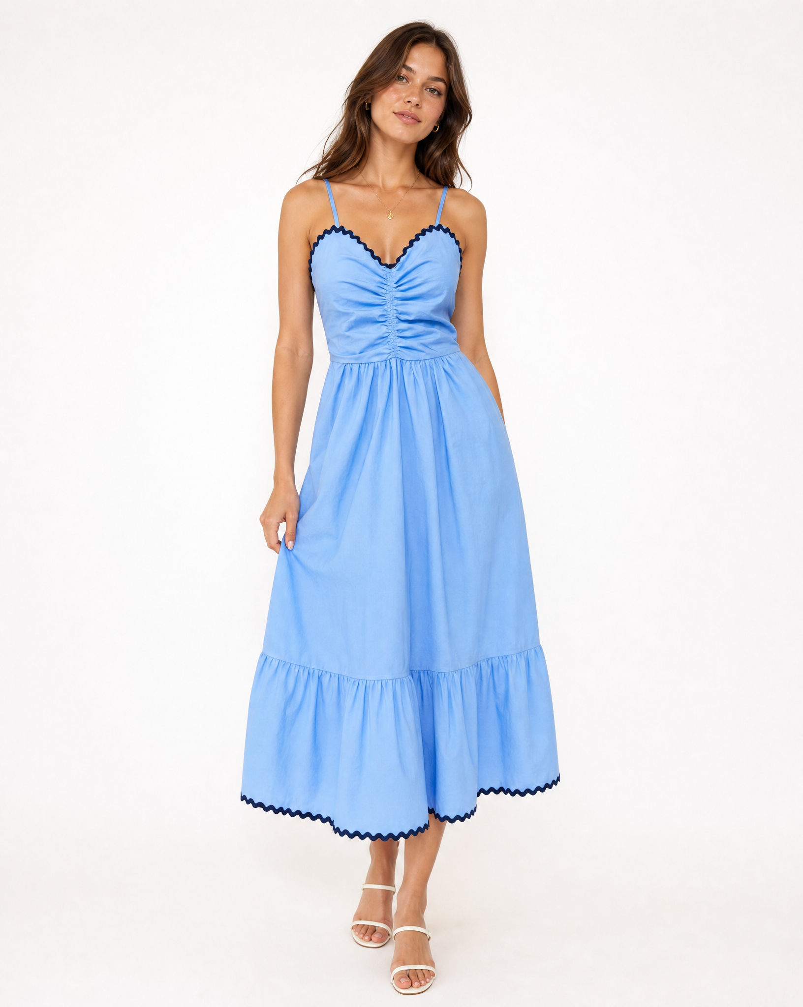 Woman in blue and navy thin strapped dress on white background