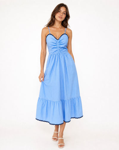 Woman in blue and navy thin strapped dress on white background